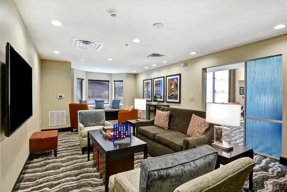 A welcoming living area with a comfortable sofa, coffee table, and eye-catching wall art. Warm lighting and an inviting setup make the space ideal for lounging, socializing, or enjoying quiet moments. The overall ambiance is cozy and perfect for relaxation or flexible sleeping arrangements.