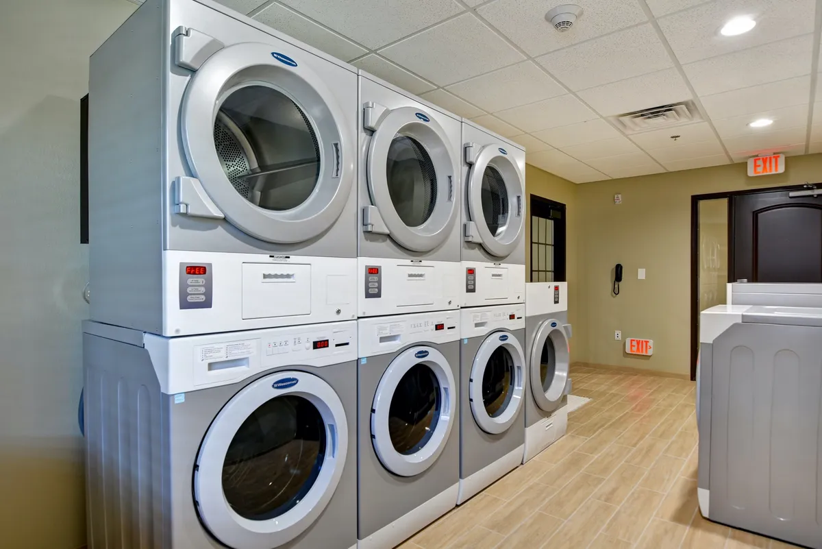 A spacious laundry facility featuring stacked washers and dryers, as well as a dedicated laundry folding area. The environment is clean and efficient, ideal for guests managing extended stays.